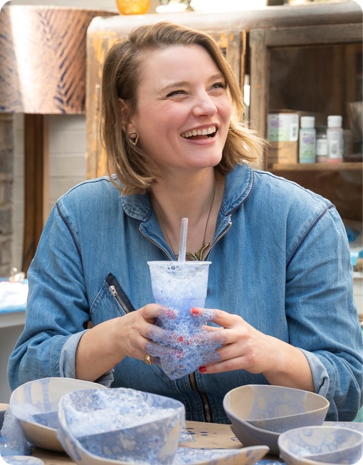 Happy person in holding colorful cup with bubbles ceramic bowls in front of her